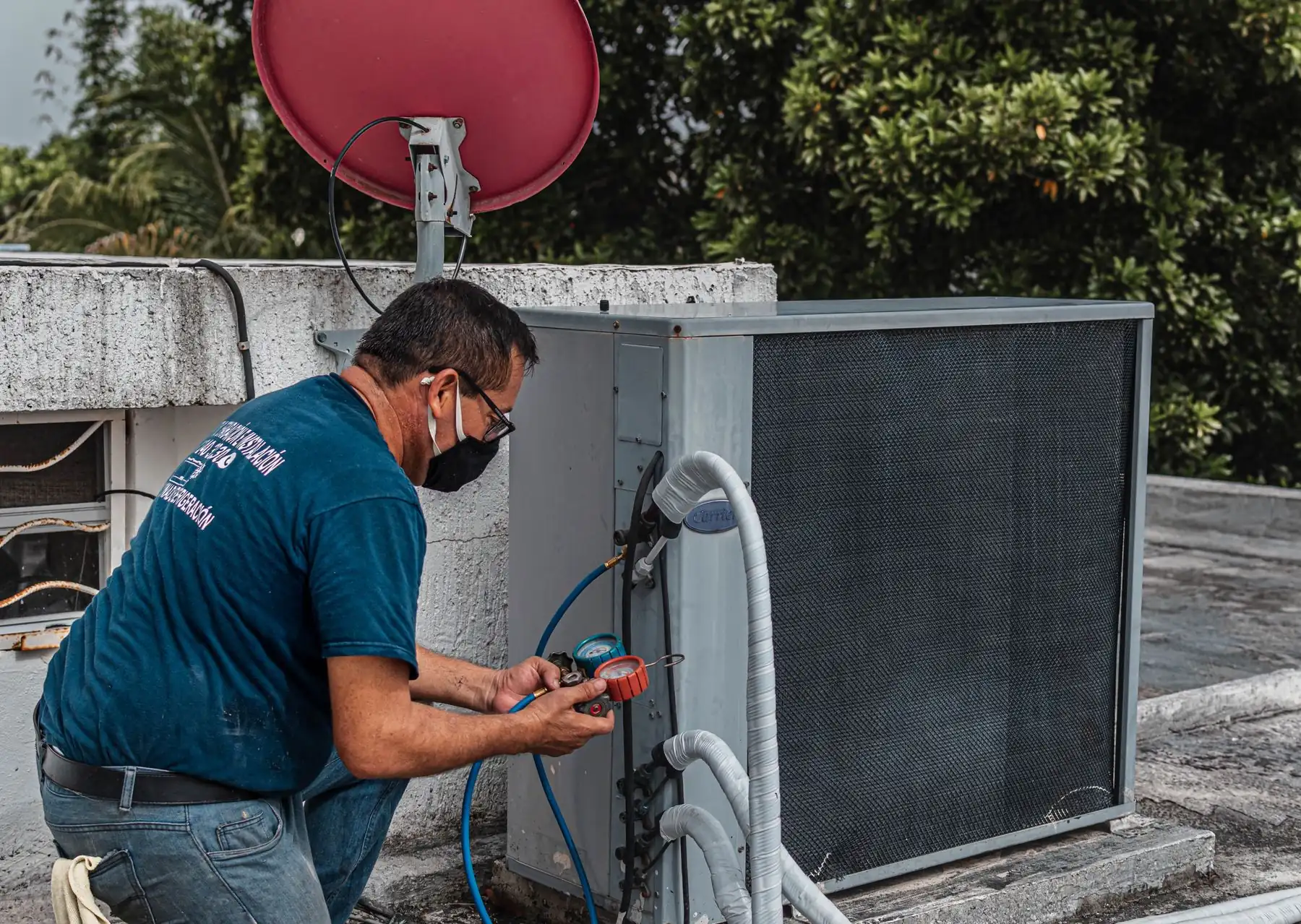 A technician checking gauge readings on an outdoor air conditioner condenser